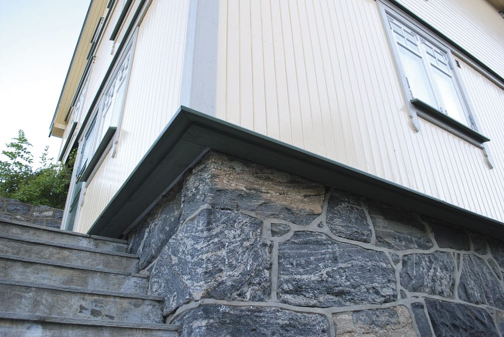 På dette bildet ses et hus hvor ytterveggen er isolert utenfra. Normalt sett ligger panelet tett på grunnmuren. Her har ettersioleringen gjort at veggen stikker svært langt ut. I dette tilfellet er vinduene flyttet tilsvarende - det er svært lite estetisk dersom vinduet blir stående innsunket inne i veggen. Foto: Per-Willy Fergestad