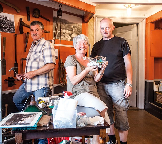 Fra venstre: Styremedlemmene Ole Ugland, Karin Kärrman (daglig leder) og Jan Fredrik Steine i ferd med å montere utstillingen av 655 flaskebåter som er donert til museet. Samlingen er nå notert i Guinness rekordbok!