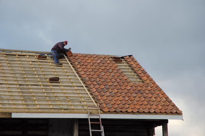 Gammel teglstein legges på taket, en lang lekte brukes som siktemål slik at radene blir rette og fine.